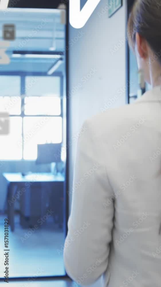 Poster animation of letters, numbers over rear view of woman using digital tablet while walking in corridor