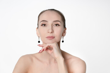 Beauty portrait of an adult woman with clear skin and soft makeup. A woman looks into the lens with...