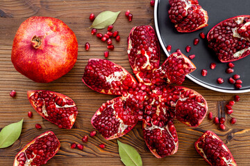 Top view of fresh ripe pomegranate and pieces on plate for eating, top view.