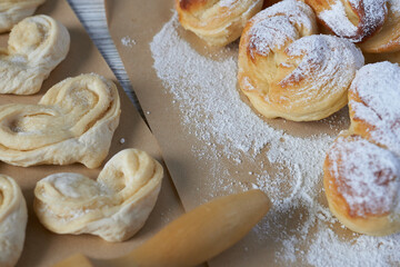 Close-up of homemade puff pastry with powdered sugar on wooden table. Vanilla buns.