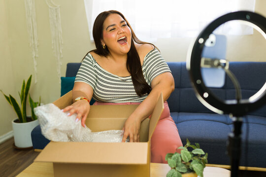 Female influencer unboxing package and filming a video for her followers