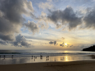 Sunset at the beach of Khao Lak, Thailand. The beach is surrounded by tropical vegetation.