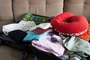 Open suitcase with clothes and accessories on sofa, close-up view