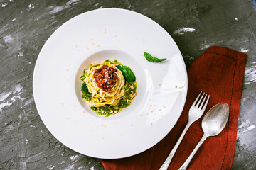Italian fituccine pasta with balognese sauce and pesto with basil and pine nuts on a gray...