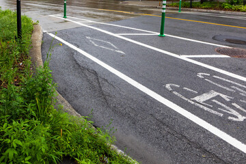 Wide cycling path with plants growing along curving sidewalk and posts along the layout on Beaubien...