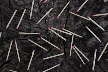 matches with pink sulfur heads lie on the wooden surface of a stump