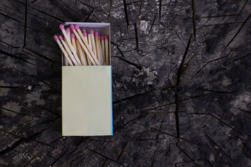matches with pink sulfur heads lie on the wooden surface of a stump