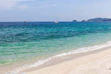 Koh Adang island, Thailand. White sand beach meets crystal-clear emerald Andaman sea. Sailboat at...
