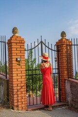 taormina, italien - frau in rotem kleid mit hut an einem eingangstor