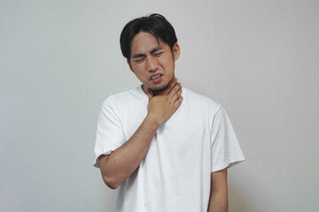 Man in white shirt clutches his throat, expressing discomfort or pain.