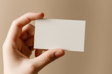 A hand holding up an empty business card, close-up shot, beige background, minimalist style, simple design.