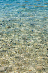 Clear turquoise water surface reveals smooth stones beneath, creating a tranquil underwater scene...