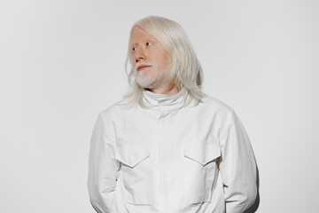 Portrait of a man with long white hair and beard wearing a white outfit against a solid white...