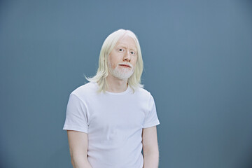 Portrait of a person with long white hair against a soft blue background, exuding a calm and serene...