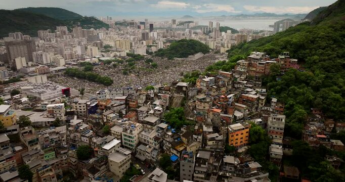 Contrast between sprawling favela, adjacent S&atilde;o Jo&atilde;o Batista cemetery, and dense cityscape of Rio de Janeiro, Brazil. Aerial backward