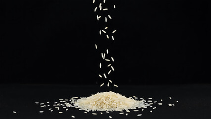 Falling rice grains on a black background create a dynamic and visually appealing composition, highlighting the texture and movement of the grains.