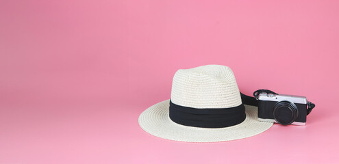 straw hat and digital camera isolated on pink background. Travelling concept.