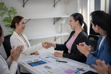 A woman shakes hands with another woman in a business meeting