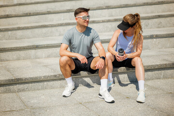 Couple takes a break on steps after an intense workout in the bright sun