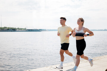 A couple enjoys a refreshing jog together along the scenic waterfront, basking in the warm glow of...