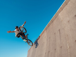 BMX bicycle rider flying and performing stunt No Hand in wooden quarter pipe. Skilled BMX...