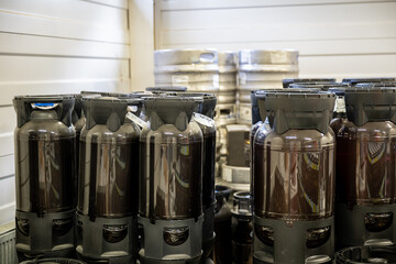 Plastic and metal beer kegs stacked in storage area at craft brewery facility