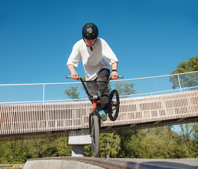 Skilled BMX rider performing Footjam trick in ramp park. Young BMX bicycle rider having fun and...