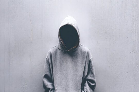 a person in a hoodie standing in front of a wall