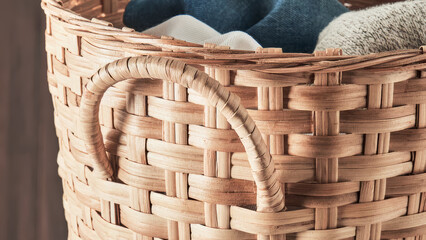 Woven basket holding neatly folded clothes placed in a cozy interior space.