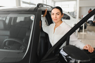 Young woman choosing a car at car showroom