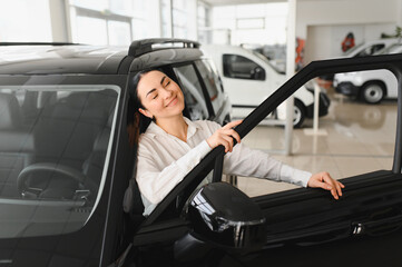 Young woman choosing a car at car showroom