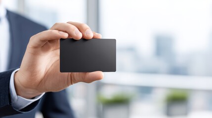 A person in business attire holds a blank black card, suggesting professionalism or a business concept with a blurred office background.