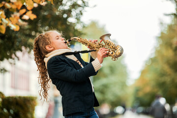Young girl playing saxophone during an outdoor performance.