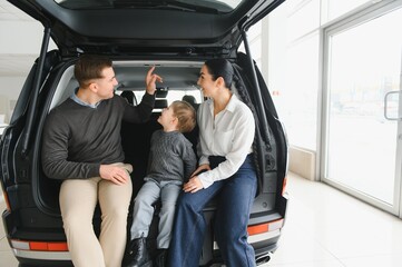 Family in a car dealership. Happy family choosing a new car in a showroom