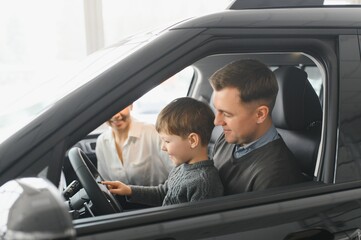 Family in a car dealership. Happy family choosing a new car in a showroom