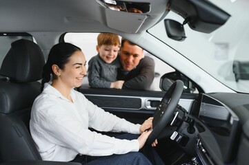 Beautiful young family choosing a new car in a car showroom
