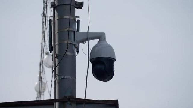 Modern outdoor security surveillance camera mounted on a tall metal pole, designed for monitoring and ensuring safety in public or private urban environments