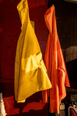 Stockholm, Sweden Yellow and orange raincoats hanging outdoors on a porch.