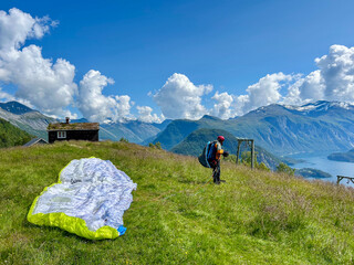 A person ready to take off with a paraglider. with beautiful mountain and fjord scenery in the background. Norwegian nature.