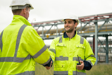 Engineer worker hand shaking to colleagues team for success work at construction site of petroleumchemical industry or refinery oil plant factory