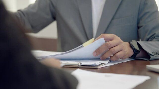 A man is holding a piece of paper in his hand. The paper is white and has a green sticker on it