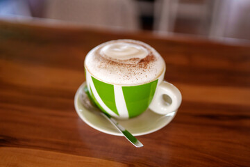 Verdant cappuccino mug dusted with cinnamon, nestled on rustic wood surface, radiating morning...