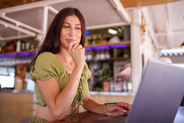 Woman in a casual setting working on a laptop, wearing a headset, suggesting a remote work...