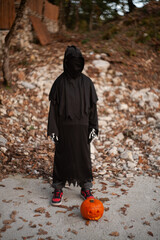 Preschool child in halloween costume at carnival with a pumpkin. Mystic, mystery, and humor in a...