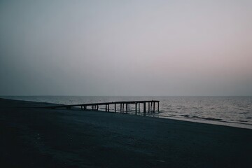 Fototapeta premium Misty beach scene with a weathered pier