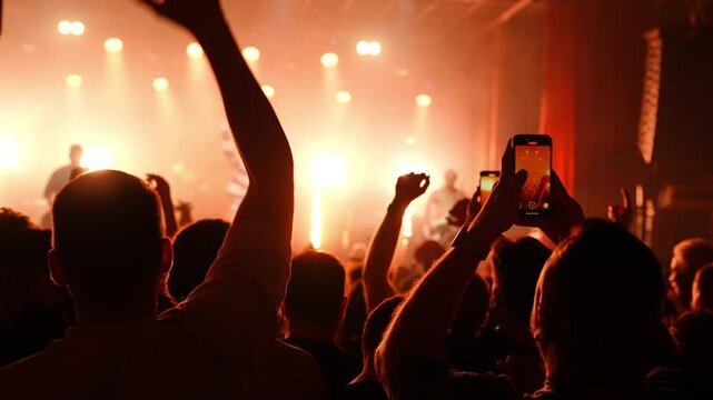 Energetic concert crowd recording live performance, holding smartphones high and capturing vibrant music festival atmosphere with passionate enthusiasm - Powered by Adobe