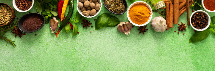 A beautiful collection of colorful spices and herbs, showcasing their natural aromas and vibrant hues on a gentle green background, top view and copy space, banner