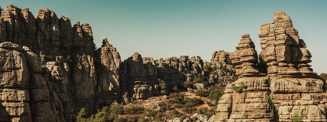 Limestone rock formations like pillars between green vegetation under a blue sky. National park El...