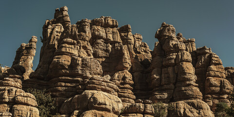 Limestone rock formations like pillars with some green vegetation under a blue sky. National park El Torcal de Antequera. Andalucia. Spain.