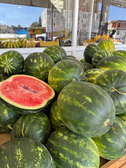 Ripe watermelons stacked on market stall, ready for sale to customers seeking fresh summer fruit.